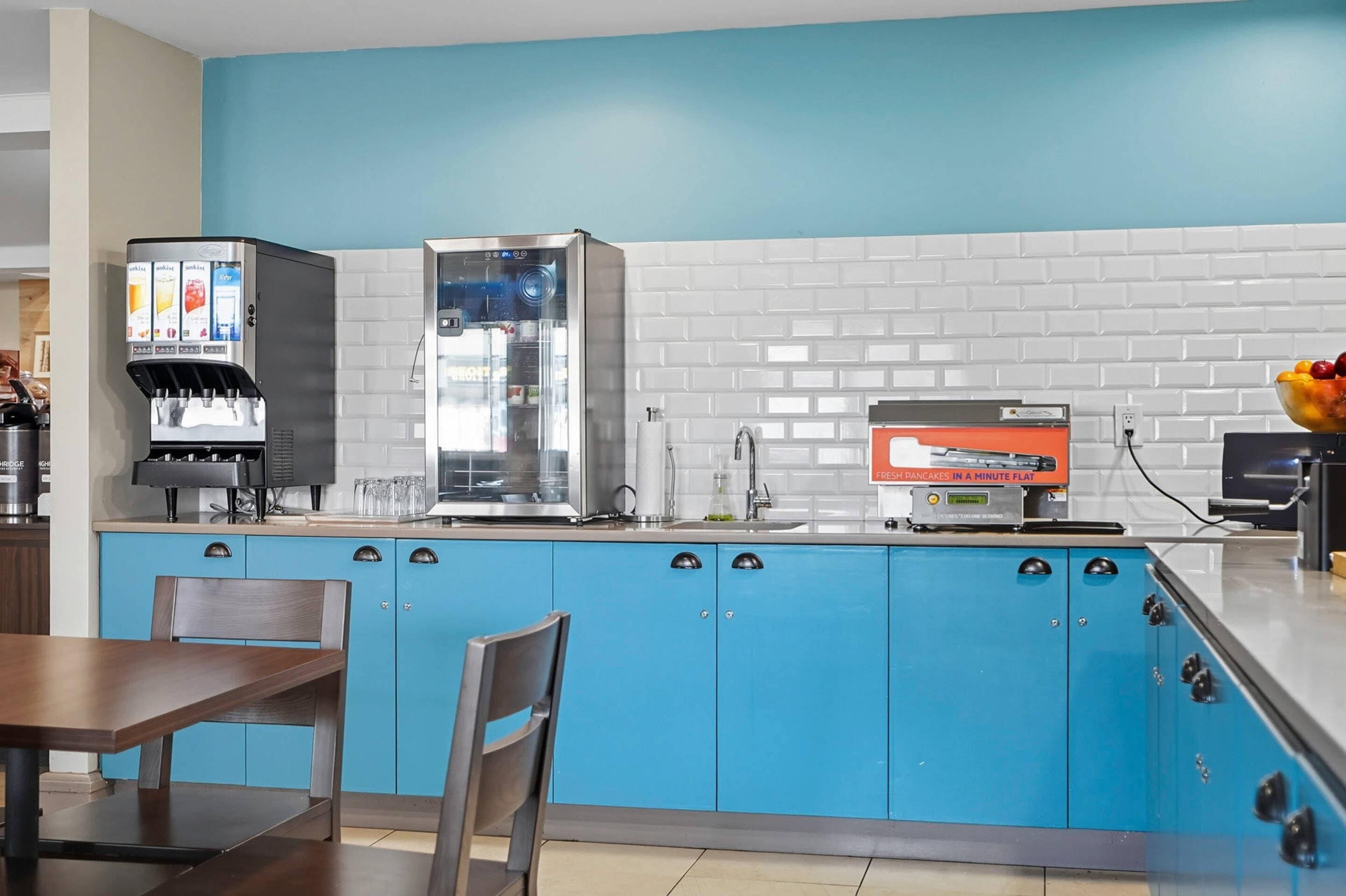 Una cocina moderna con armarios azules, una cafetera, un microondas y un televisor de pantalla plana.