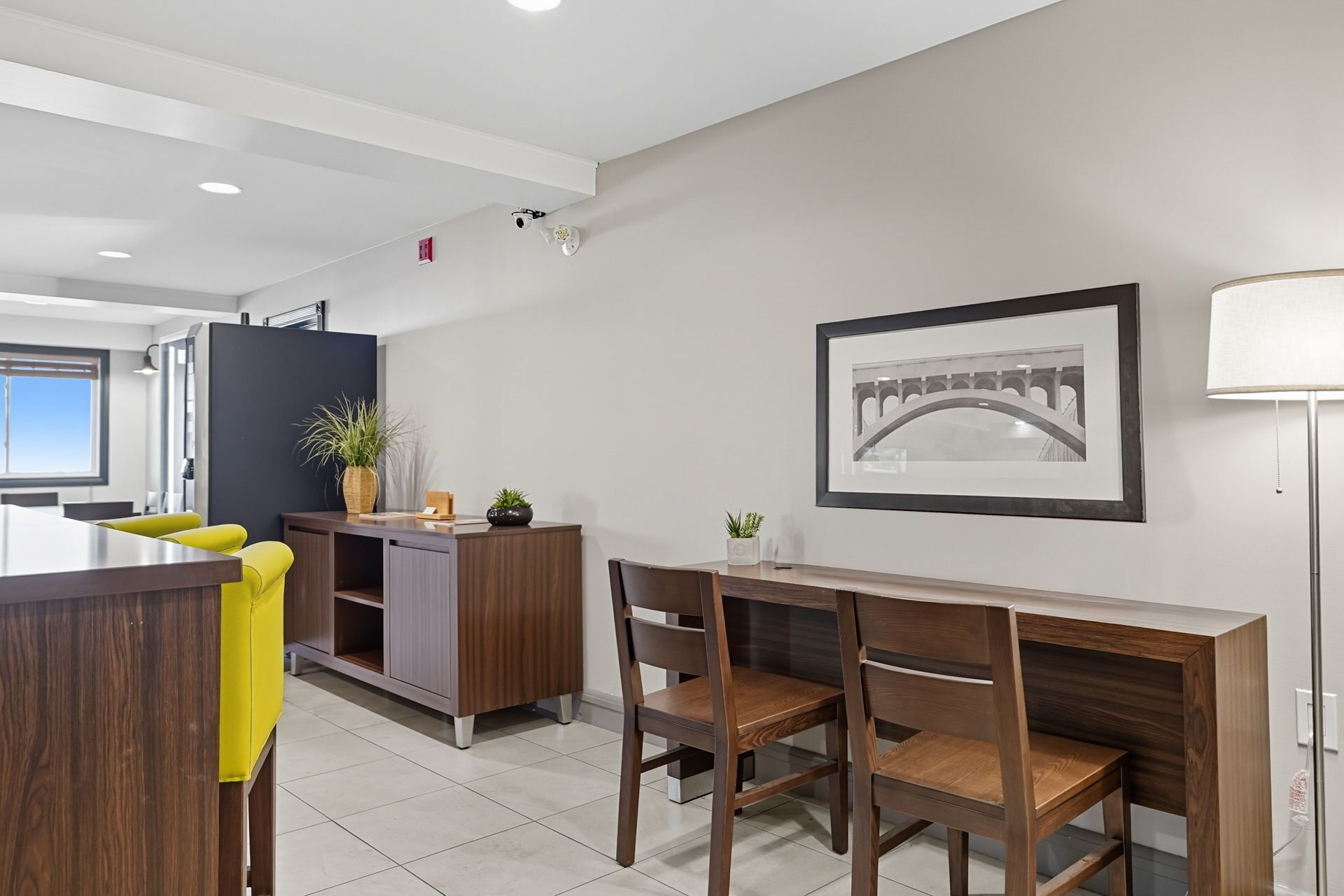 Un espace repas moderne avec une table et des chaises en bois, un meuble de couleur sombre et un tableau encadré au mur.