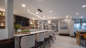 A modern bar area with a long counter, multiple stools, and a television screen. - Holiday Inn & Suites Winnipeg Downtown by IHG (Winnipeg)