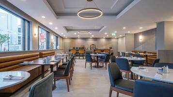 Um restaurante moderno com cabines e mesas, janelas amplas e um design limpo e contemporâneo.