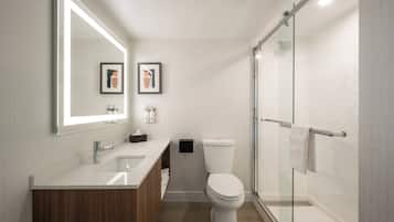 A modern bathroom with a large mirror, a sink, a toilet, and a glass-enclosed shower.