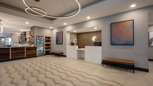 A modern hotel lobby with a reception desk, seating area, and a patterned floor. - Holiday Inn & Suites Winnipeg Downtown by IHG (Winnipeg)
