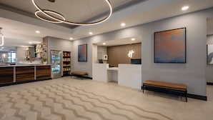 Un moderno vestíbulo de hotel con mostrador de recepción, zona de estar y suelo estampado.