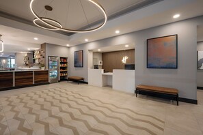 A modern hotel lobby with a reception desk, seating area, and a patterned floor. - Holiday Inn & Suites Winnipeg Downtown by IHG (Winnipeg)