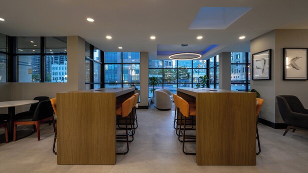 A modern interior with wooden tables and chairs, large windows, and framed artwork on the walls. - Holiday Inn & Suites Winnipeg Downtown by IHG (Winnipeg)