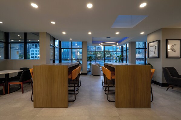 A modern interior with wooden tables and chairs, large windows, and framed artwork on the walls. - Holiday Inn & Suites Winnipeg Downtown by IHG (Winnipeg)