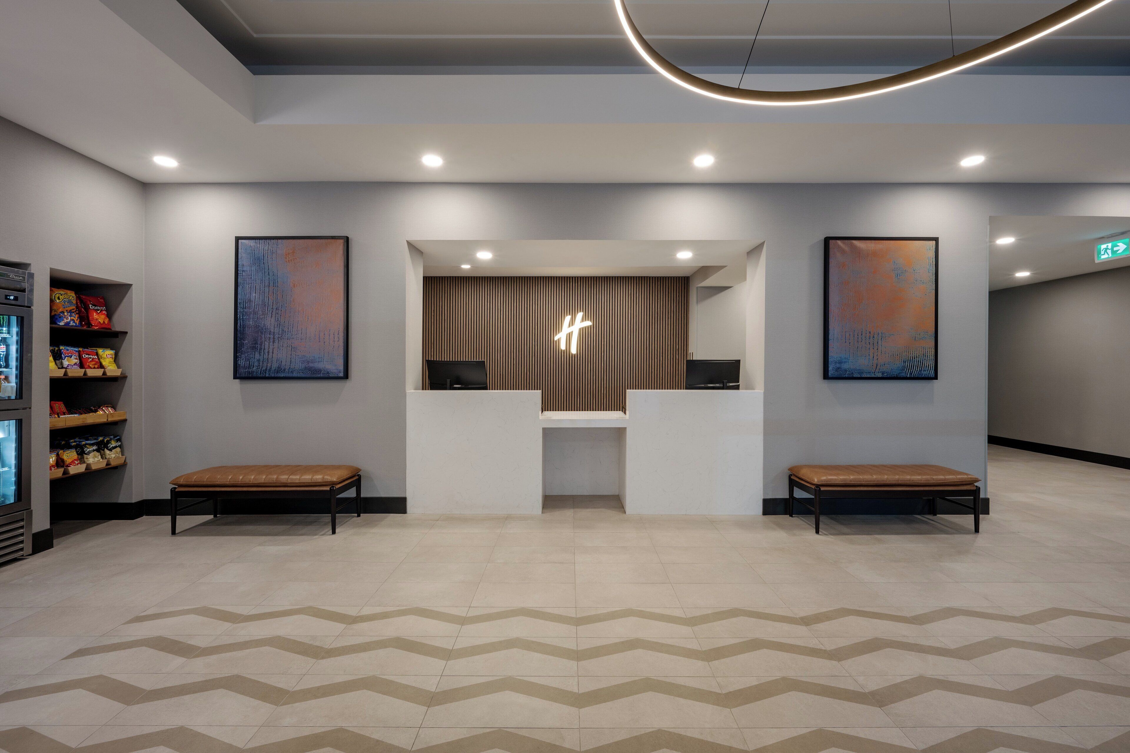 A reception area with a modern design, featuring a reception desk, two benches, and artwork on the walls.