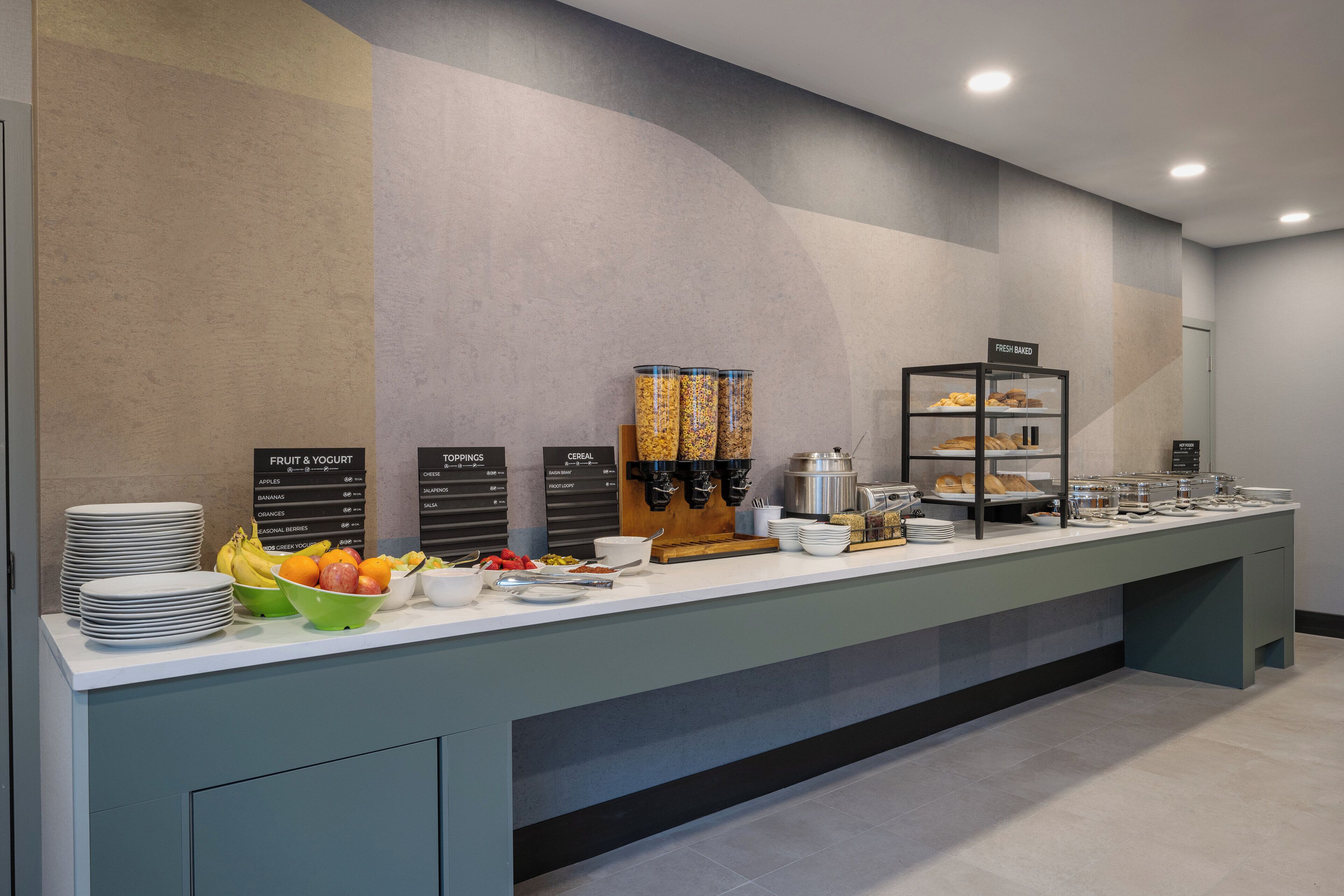 A buffet setup with labeled sections for fruit & yogurt, toppings, and cereal.