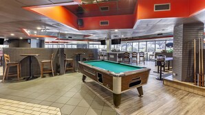 Une table de billard dans une pièce comprenant un bar, des chaises et une cheminée.