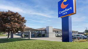 Un hôtel Comfort Inn, reconnaissable à son grand panneau bleu, doté d’un parking et d’un bâtiment aux nombreuses fenêtres et au toit plat.