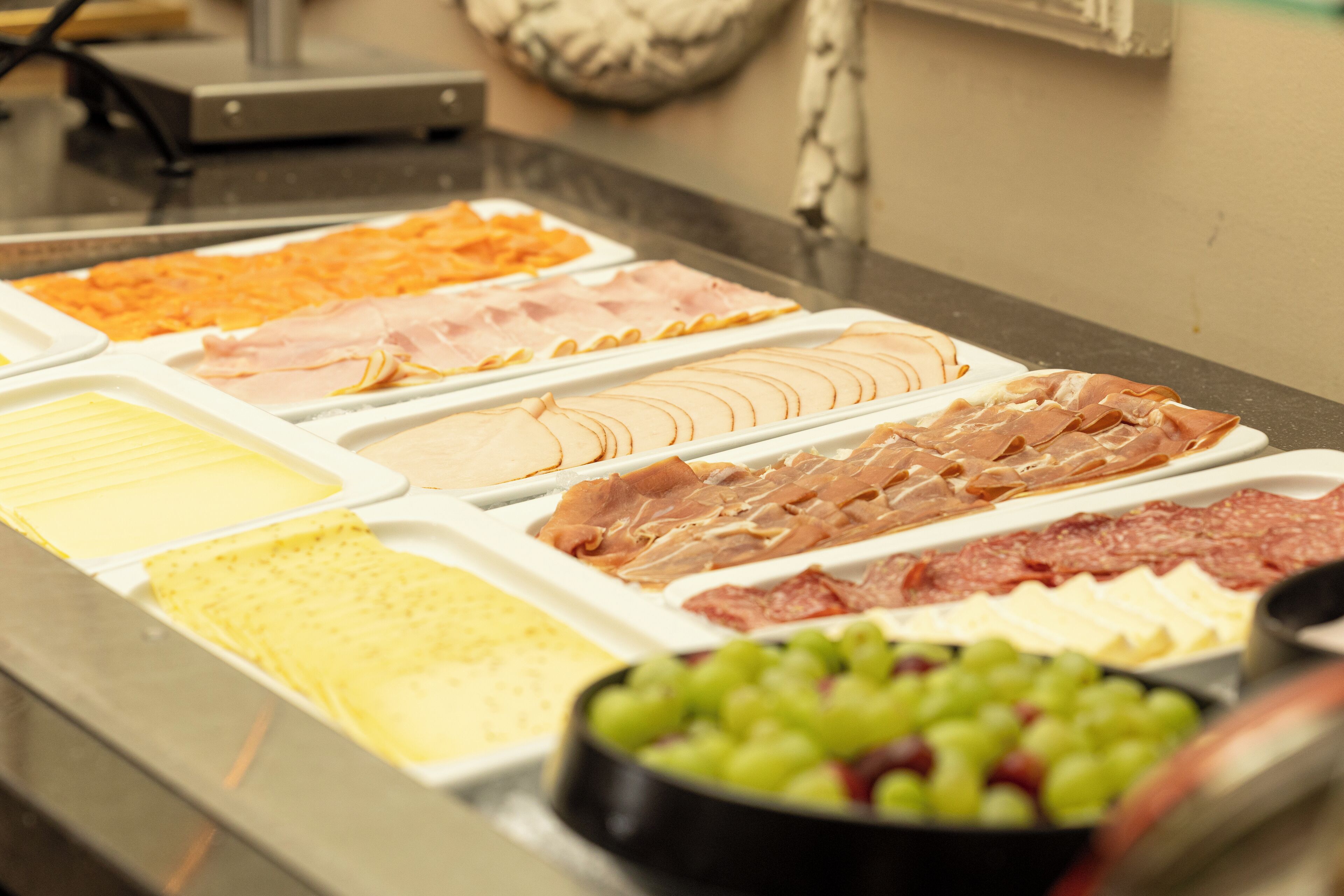 Ein Buffet mit verschiedenen Speisen, darunter Fleisch, Käse und Obst.