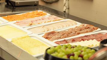 Ein Buffet mit verschiedenen Speisen, darunter Fleisch, Käse und Obst.
