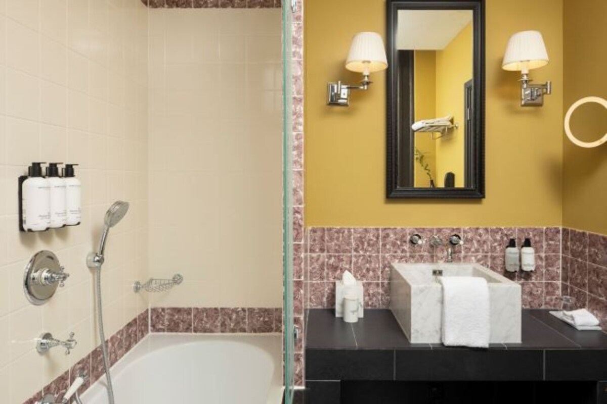 A bathroom with a bathtub, a sink with a mirror, and toiletries on the wall.