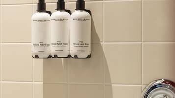 Trois bouteilles de gel douche et d’après-shampoing de la marque Marie-Stella-Maris, posées sur un mur carrelé.