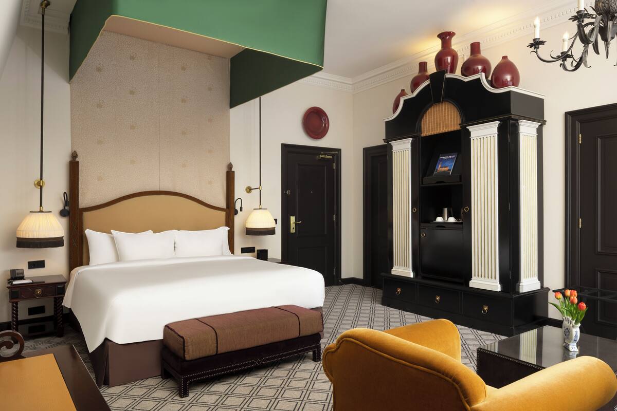 Une chambre d’hôtel équipée d’un grand lit, d’un bureau, d’une chaise, d’une coiffeuse et d’un téléviseur.