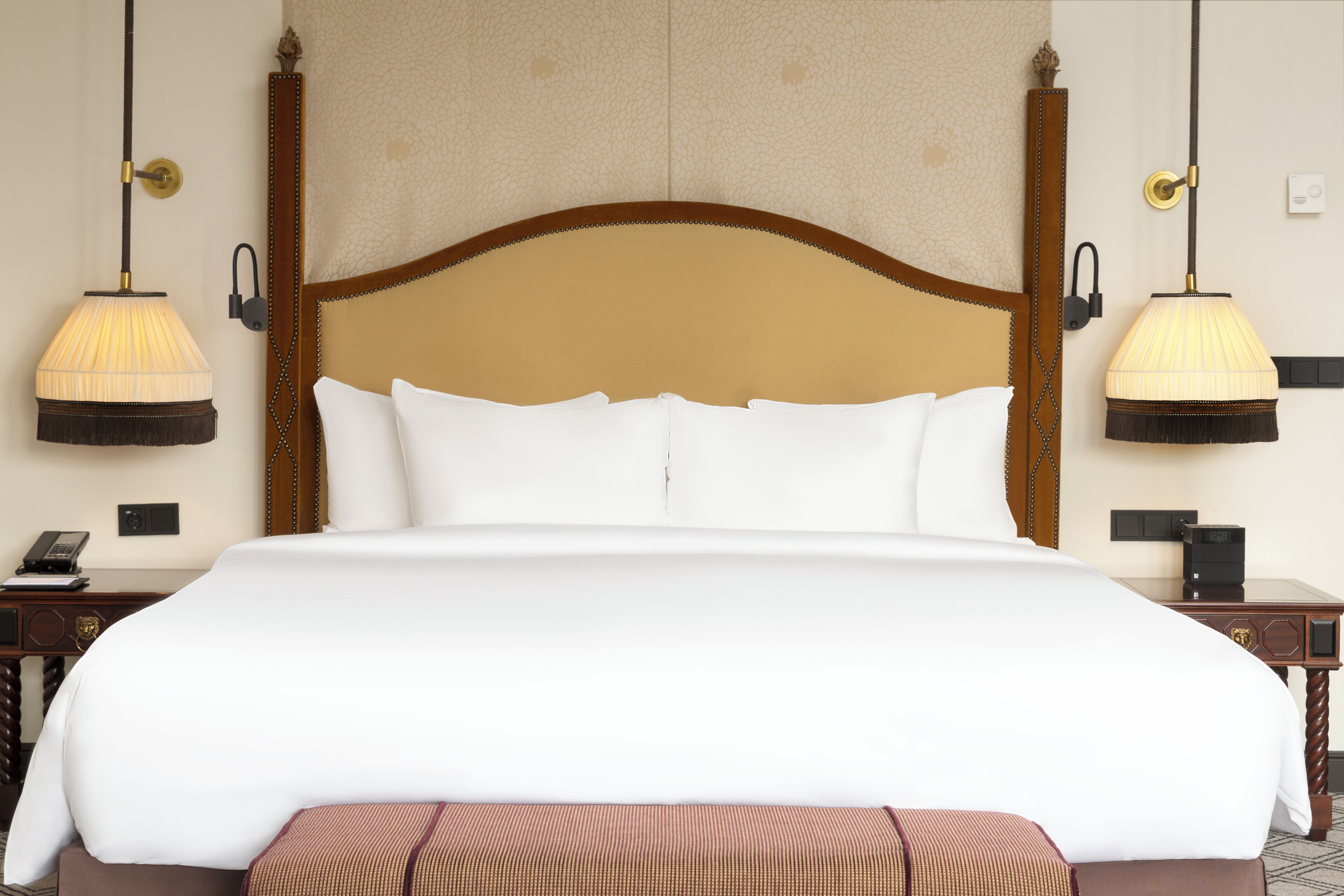 A large bed with white linens, two bedside lamps, and a wooden headboard.