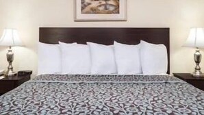 A hotel room with a bed, two bedside lamps, a framed picture on the wall, and a patterned bedspread. - Days Inn by Wyndham Indianapolis/Castleton (Indianapolis)