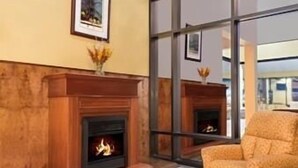 A room with a fireplace, a framed picture on the wall, and a window with a view. - Days Inn by Wyndham Indianapolis/Castleton (Indianapolis)