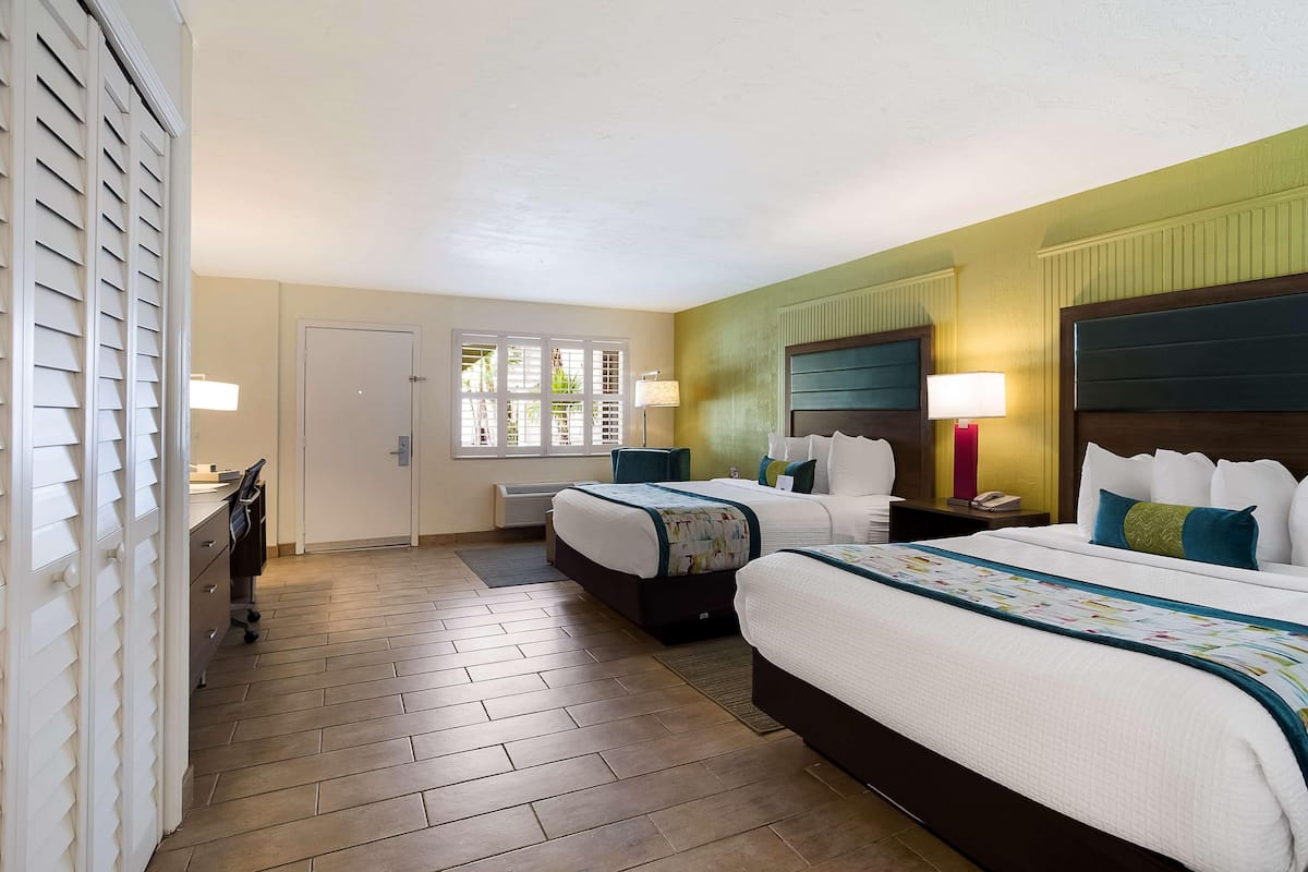 A hotel room with two beds, a desk, and a chair.