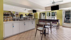 A modern kitchen with a central island, white cabinets, and a dining area with wooden chairs and a table. - Best Western Hibiscus Motel (Key West)
