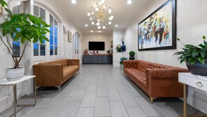 A spacious living room with a large window, a modern chandelier, and a large painting on the wall. - Super 8 by Wyndham New Orleans (New Orleans)