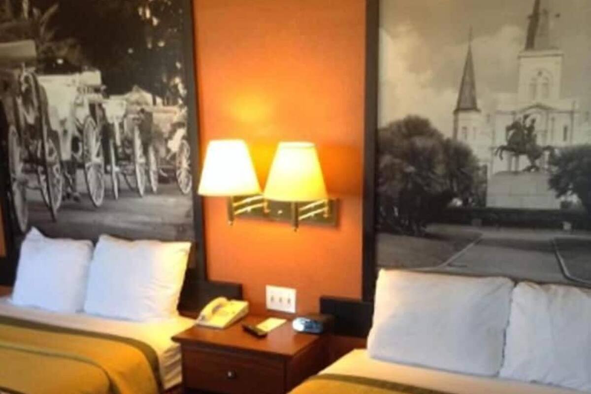 Une chambre d’hôtel avec deux lits, une table de chevet avec une lampe et deux lampes fixées au mur.
