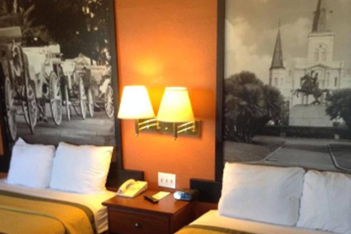 Une chambre d’hôtel avec deux lits, chacun recouvert d’une couvre-lit à motifs, une table de chevet avec une lampe et un téléphone fixé au mur.