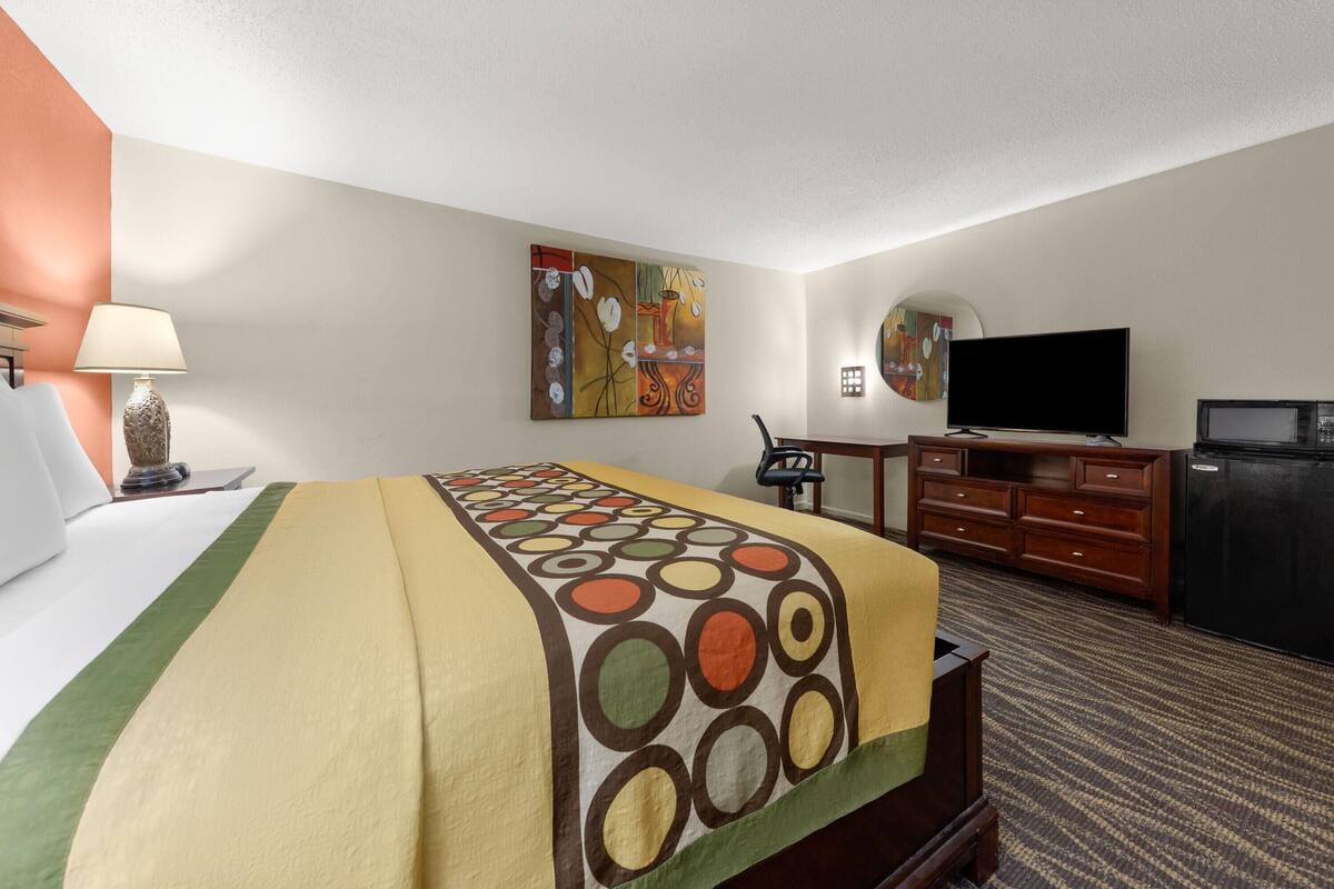 Une chambre d’hôtel équipée d’un lit, d’un bureau, d’une télévision et d’un four à micro-ondes.