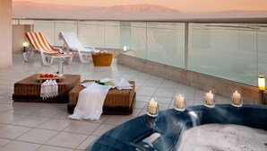 Eine Dachterrasse mit Liegestühlen, einem Whirlpool und einem Korbwannenstuhl.