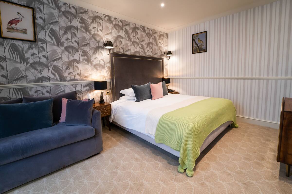 Un dormitorio con cama, sofá y mesita de noche.