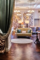 A luxurious living room with a tufted sofa, patterned wallpaper, and elegant chandeliers.