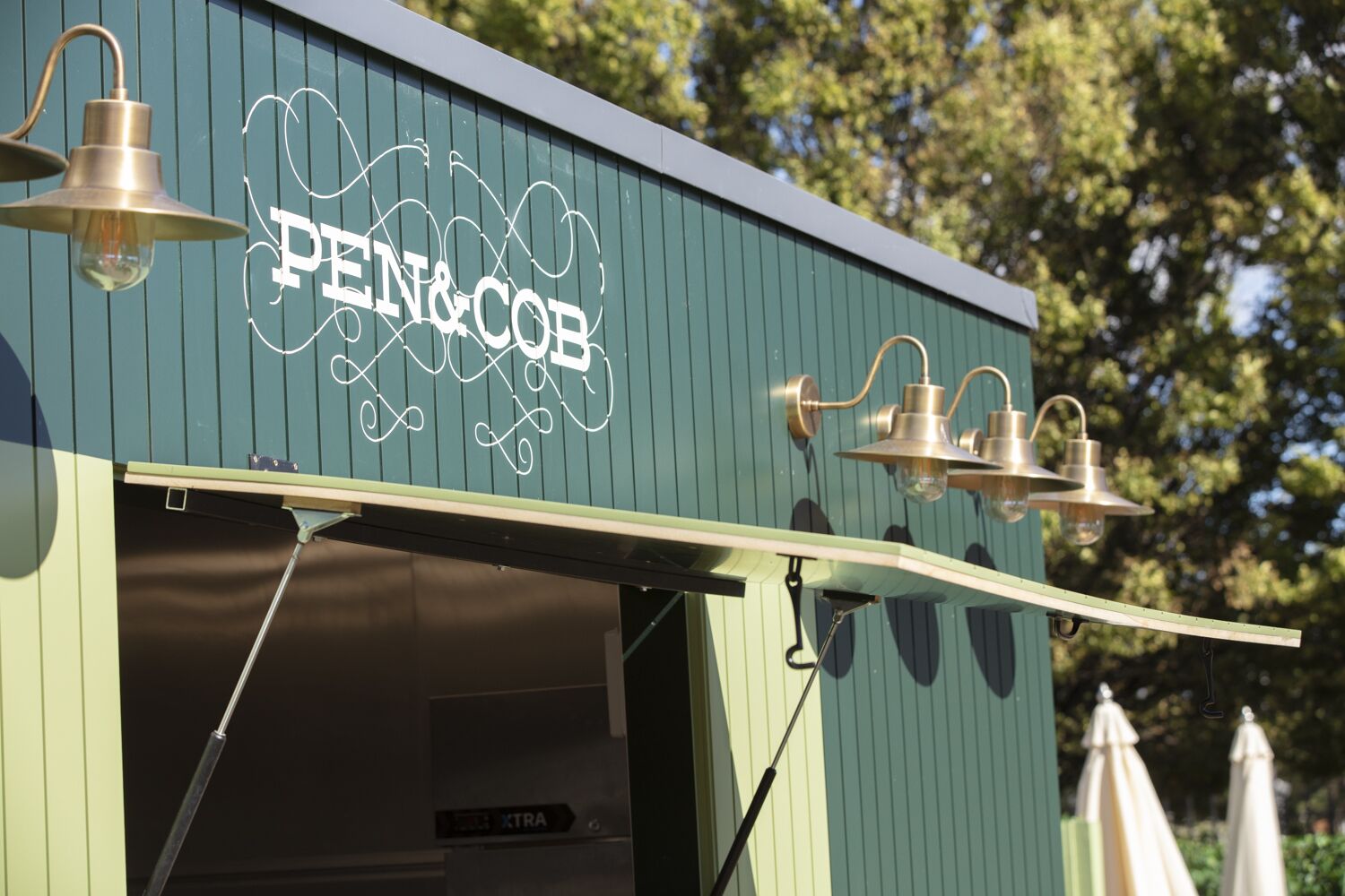 A building with a sign reading "PEN & COB" and two outdoor light fixtures.