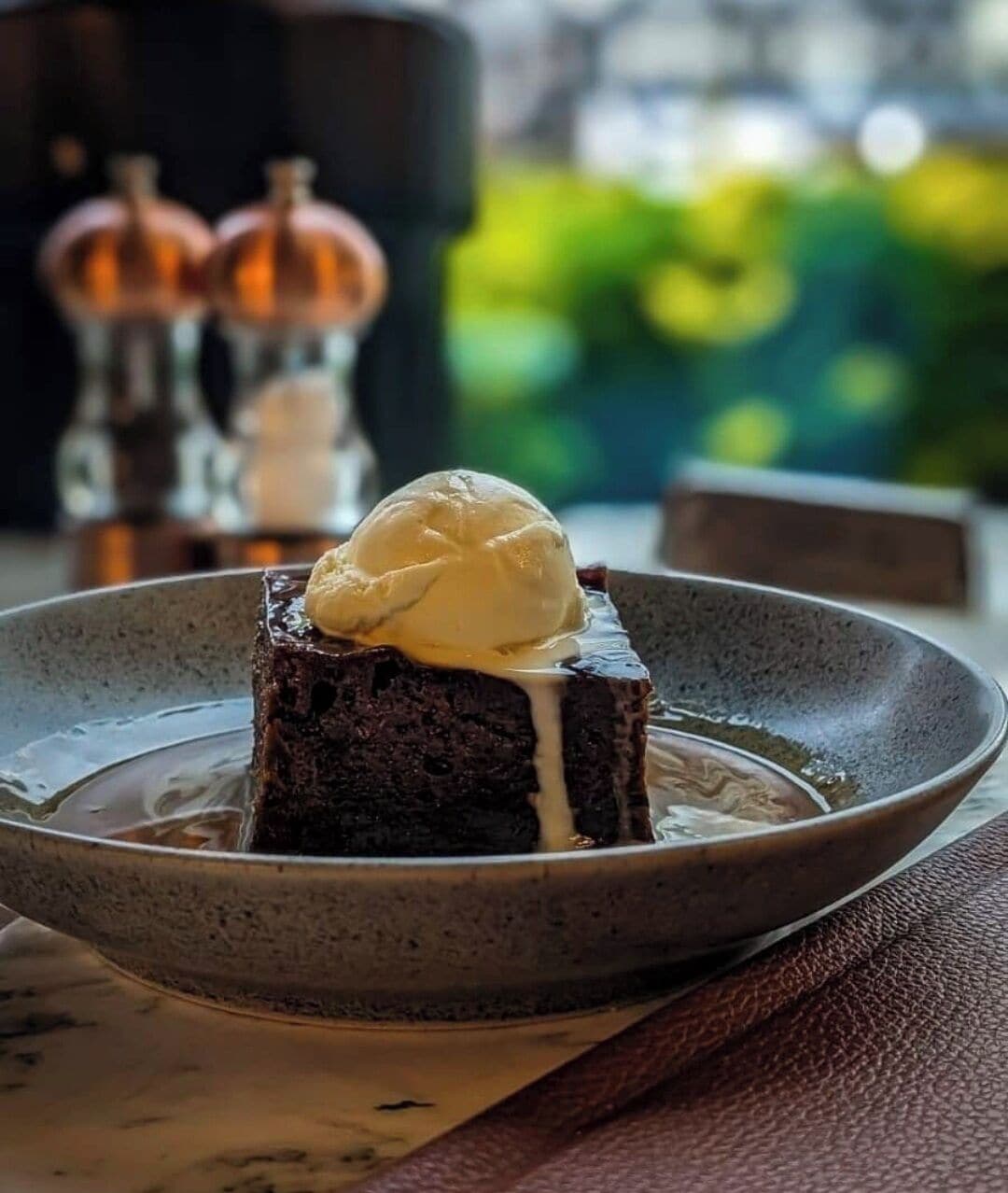 Un postre con una porción de helado encima, servido en un plato.
