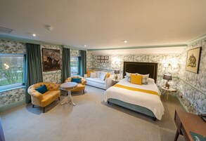 A hotel room with a bed, two sofas, a round table, and a small side table.