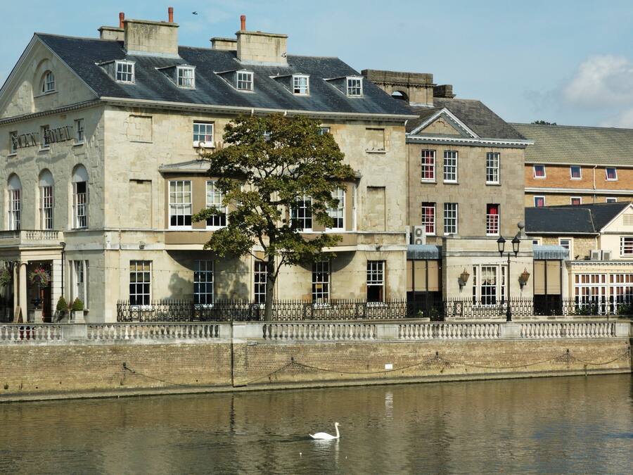 A historic building with a stone facade, large windows, and a tree in front.