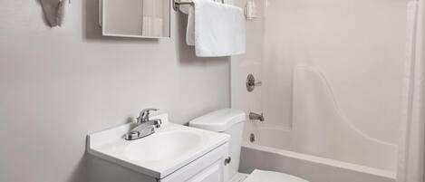 Un baño moderno con inodoro, lavamanos y ducha.