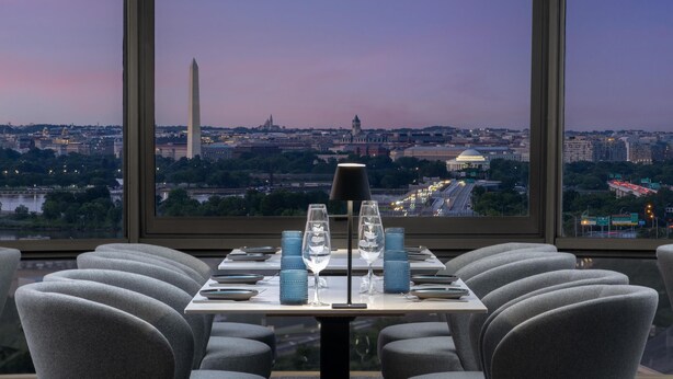 En restaurang med ett bord dukat för två personer, utsikt över Washingtonmonumentet och en stadsbild i bakgrunden.