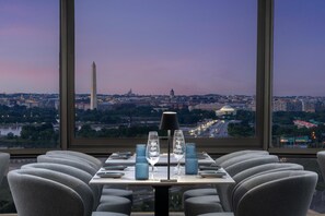 A restaurant with a table set for two, a view of the Washington Monument, and a cityscape in the background. - DoubleTree by Hilton Washington DC - Crystal City (Arlington)