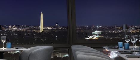 A dining area with a view of the Washington Monument at night.
