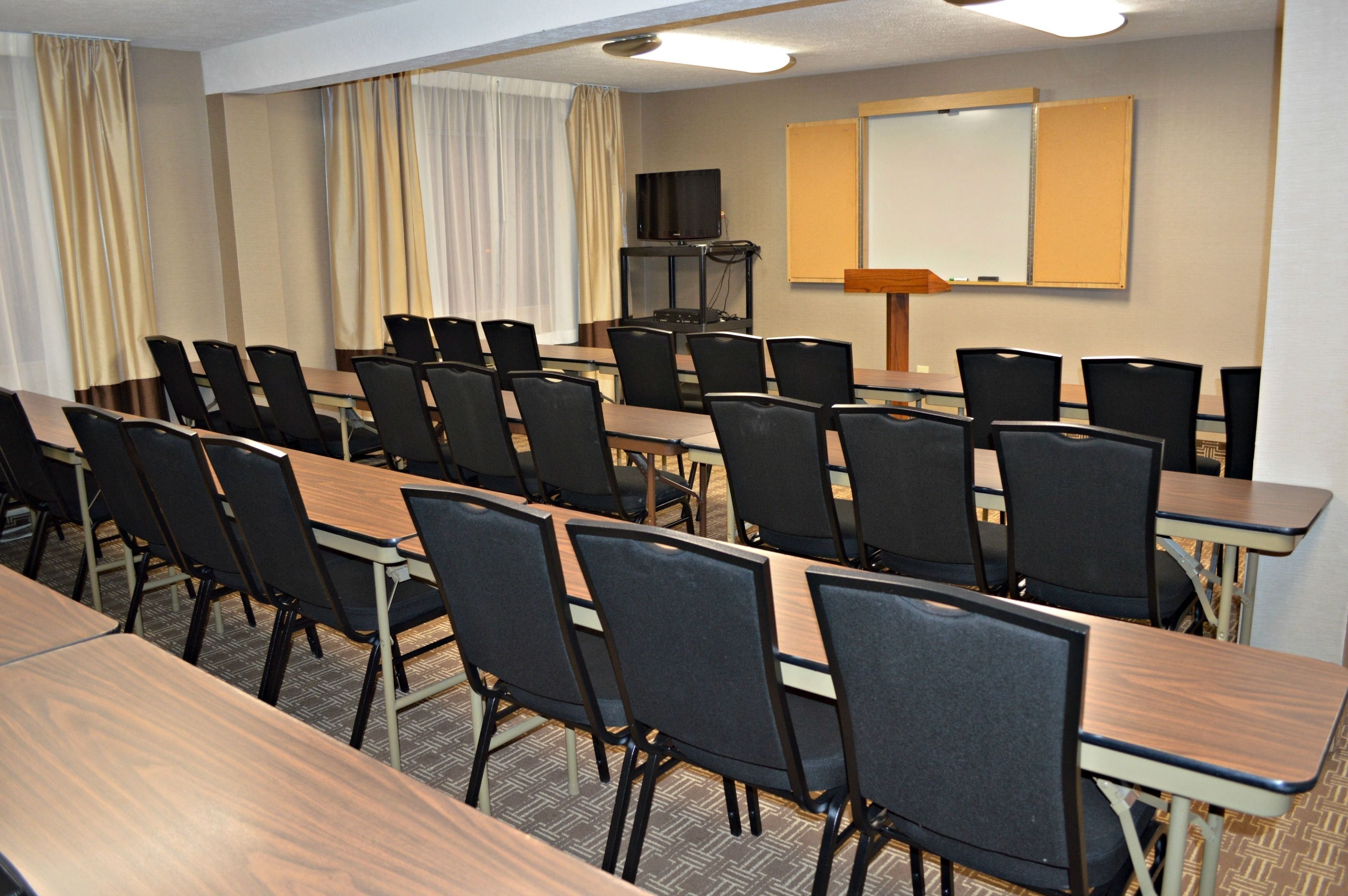 A conference room with multiple tables and chairs, a television, and a projection screen.