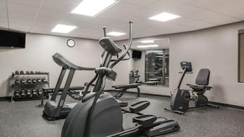 A gym with treadmills, elliptical machines, and dumbbells.