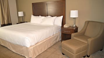 Une chambre d’hôtel avec un grand lit, deux tables de chevet, une chaise et une lampe.