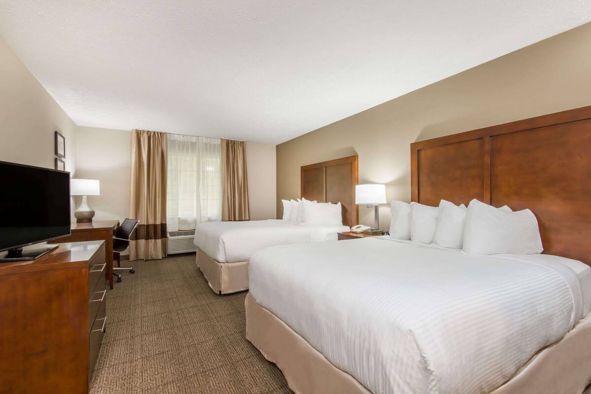 Een hotelkamer met twee bedden, een bureau met een televisie en een stoel.