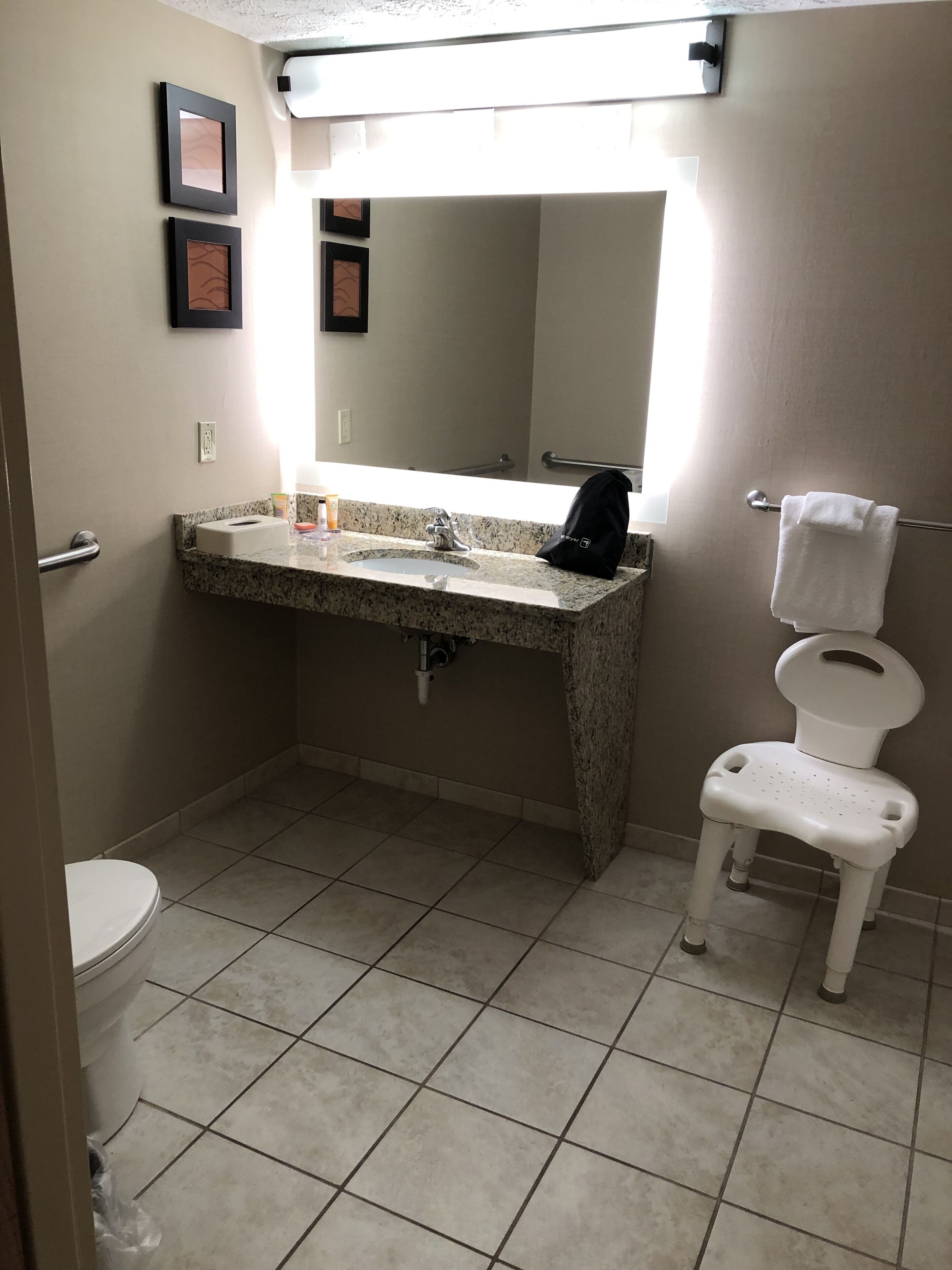 A bathroom with a sink, mirror, toilet, and a small step stool.