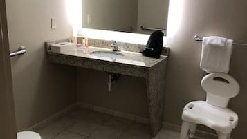 A bathroom with a sink, mirror, toilet, and a small step stool.