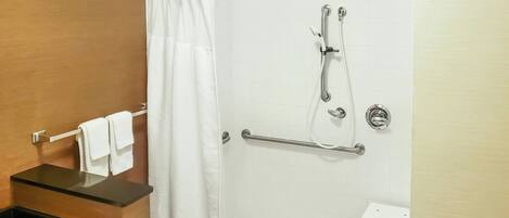 A shower with a grab bar, a towel rack, and a white shower curtain.