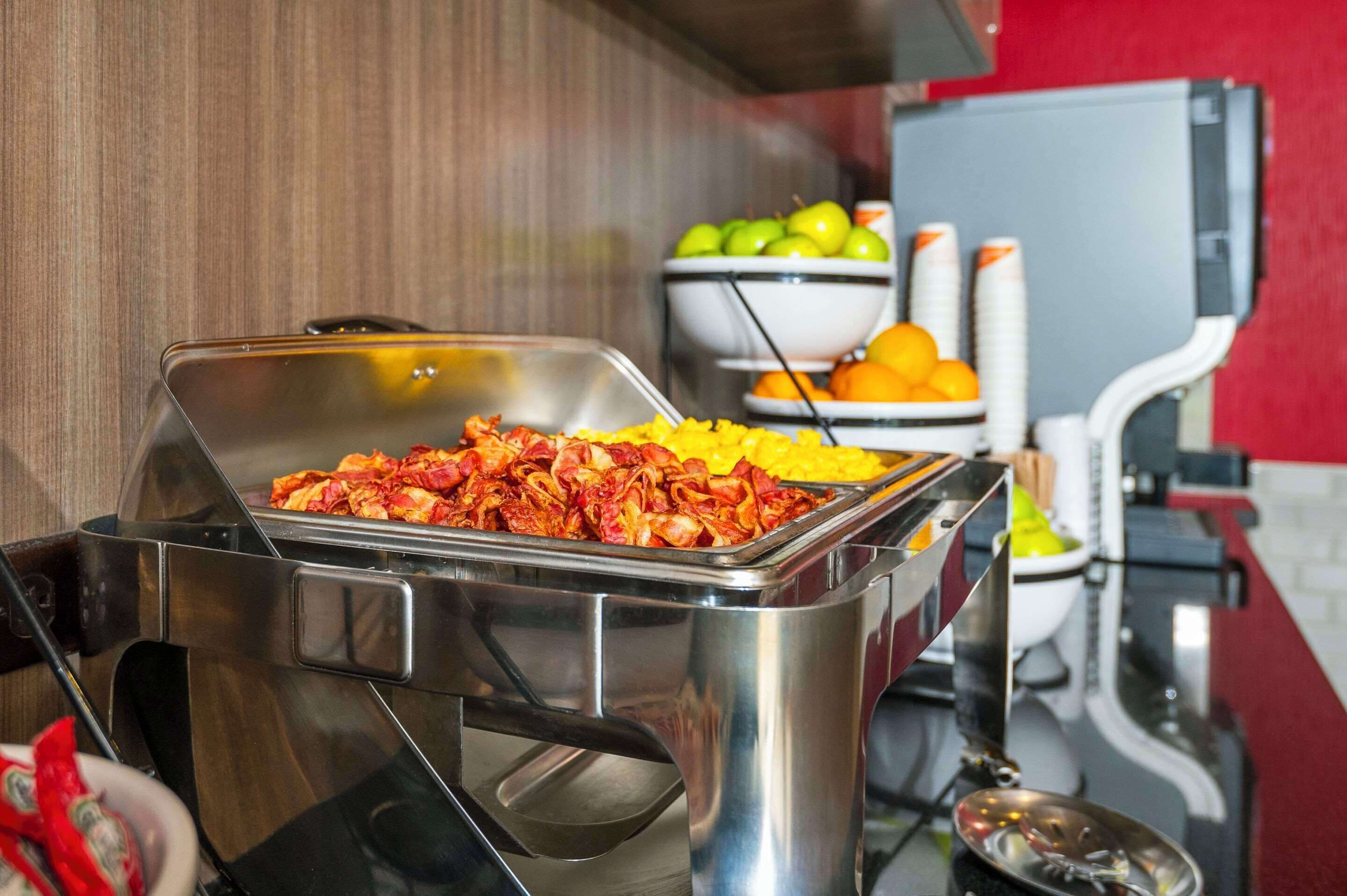 Montaje de bufé con diversos alimentos, incluyendo una bandeja de carne roja y un tazón de fruta.