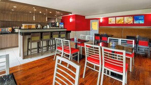 A modern restaurant with a bar area, red and white chairs, and a wooden floor.