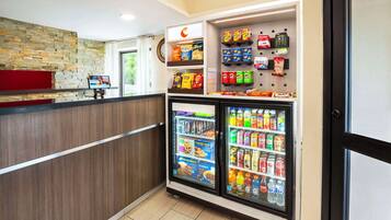 Zona de máquinas expendedoras con refrigerios y bebidas, un reloj y una pantalla digital.