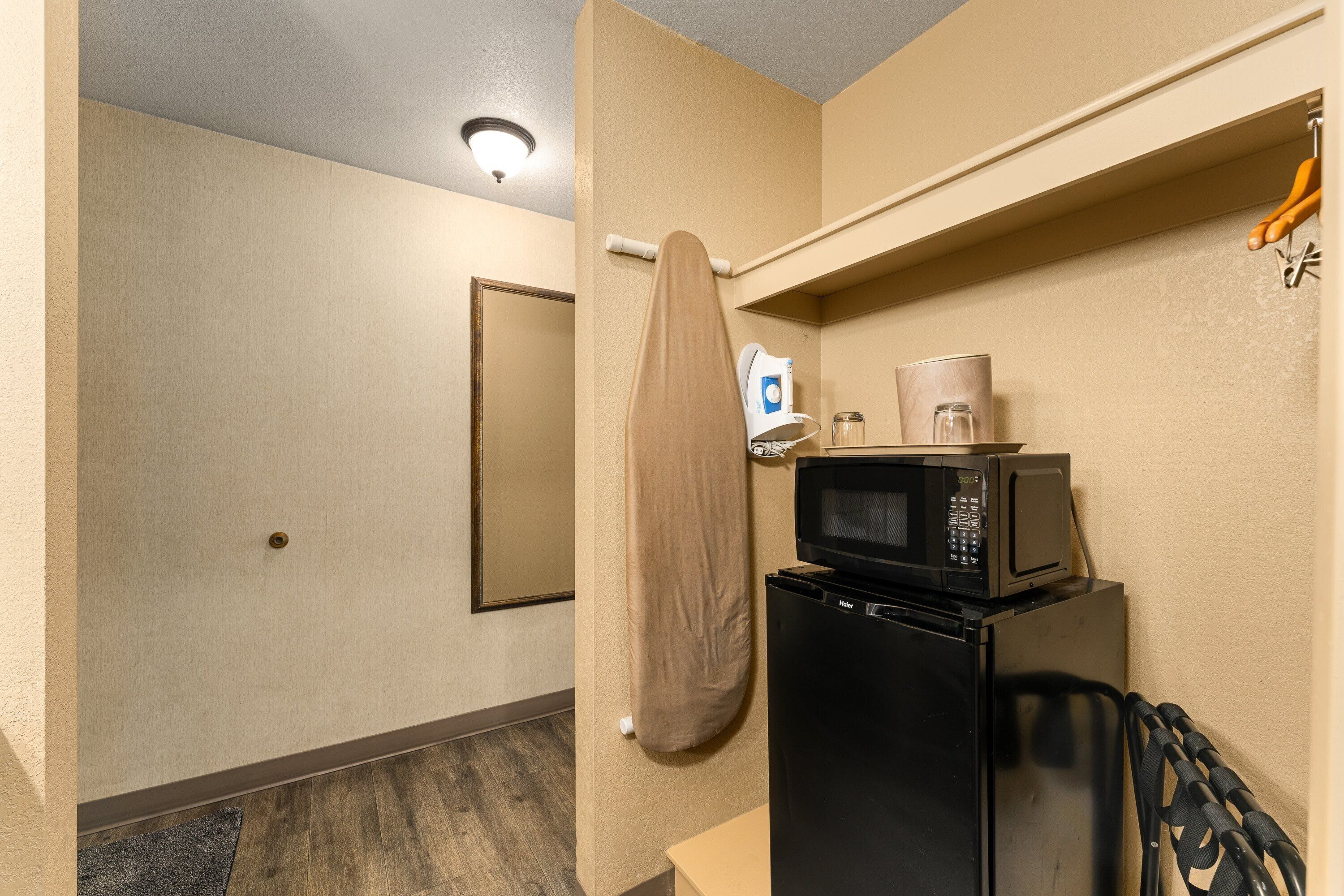 A compact kitchenette with a microwave, refrigerator, and a towel hanging on a hook.